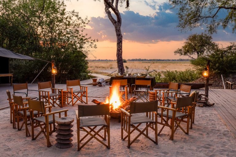 Botswana safari: camp fire circle with safari chairs at sunset
