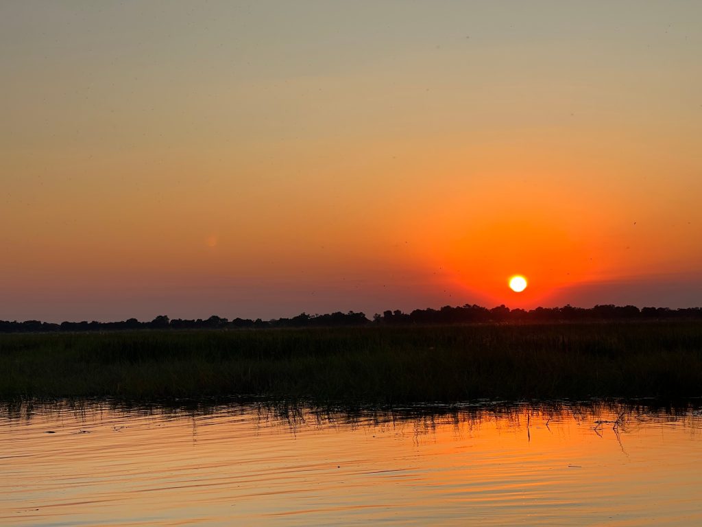 Botswana safari: orange sunset over delta floodplain water