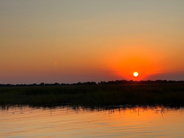 Botswana safari: orange sunset over delta floodplain water