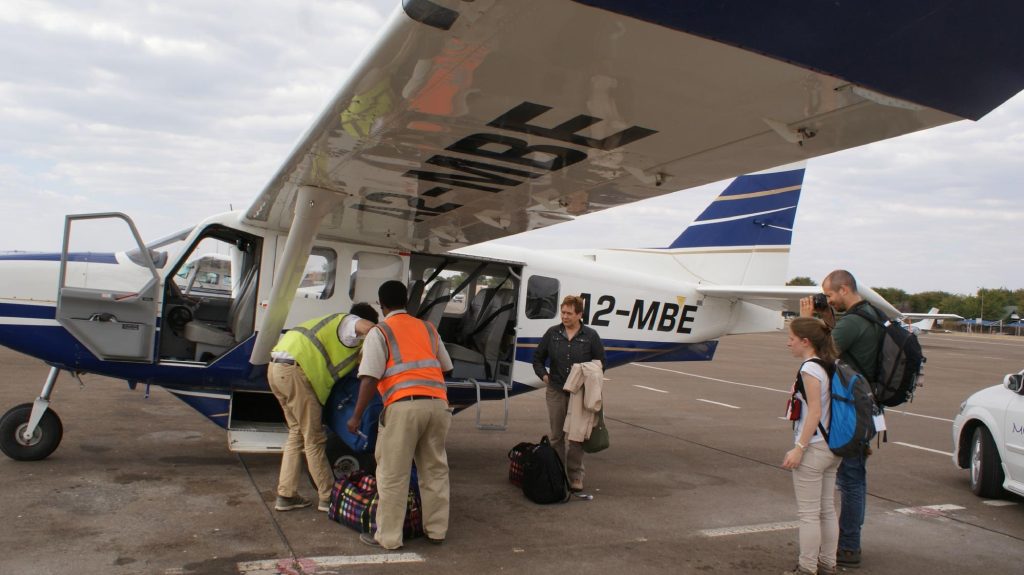 Botswana safari: passengers and bush pilot beside Cessna at airstrip